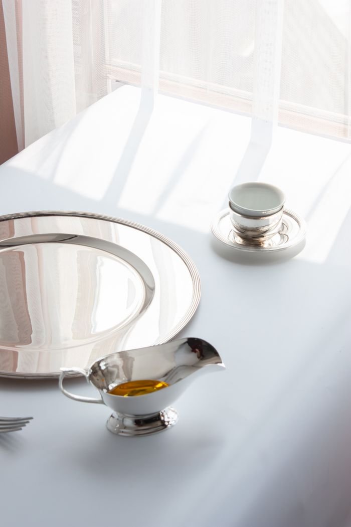 Home A minimalist setup featuring elegant silverware and a cup on a sunlit table.